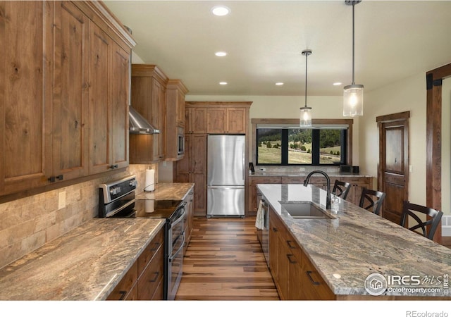 kitchen with sink, hanging light fixtures, stainless steel appliances, light stone counters, and decorative backsplash