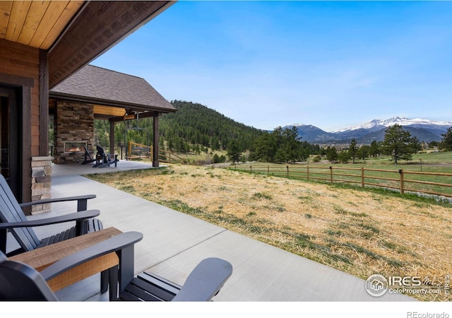 view of yard with a rural view, a mountain view, a patio area, and an outdoor stone fireplace