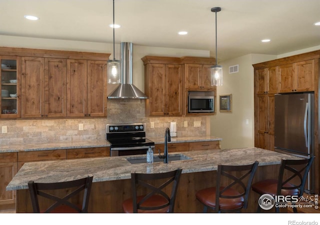 kitchen featuring decorative light fixtures, appliances with stainless steel finishes, sink, and wall chimney exhaust hood