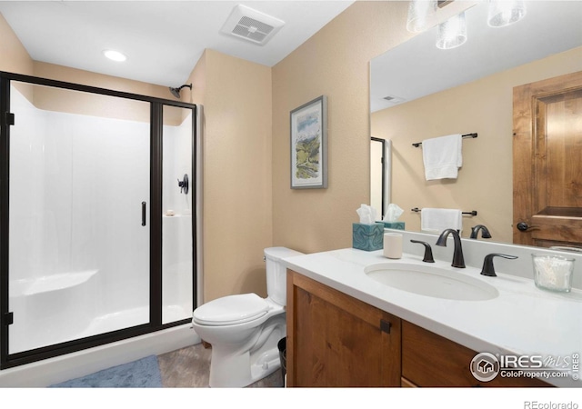 bathroom featuring vanity, toilet, and a shower with door