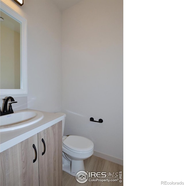 bathroom with hardwood / wood-style floors, toilet, and vanity