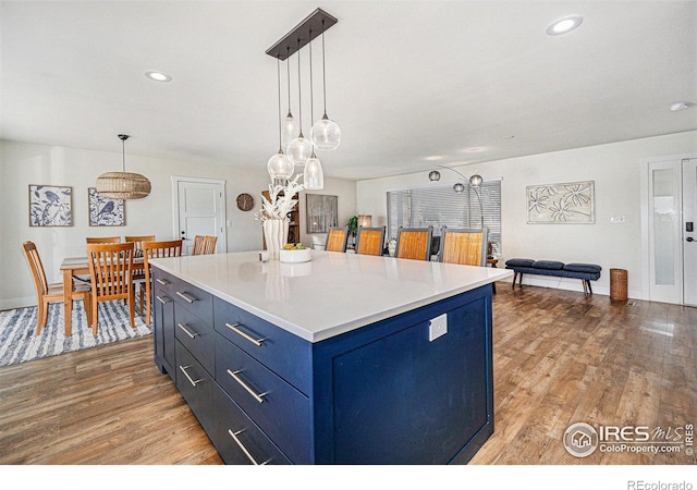 kitchen featuring blue cabinets, pendant lighting, light countertops, and light wood-style flooring