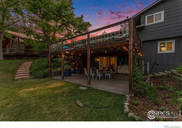 back of house with a yard, a patio, stairway, board and batten siding, and a wooden deck