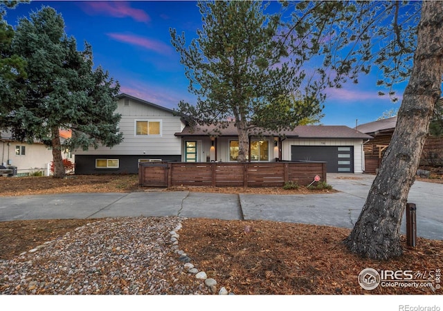 tri-level home featuring an attached garage, driveway, and a fenced front yard