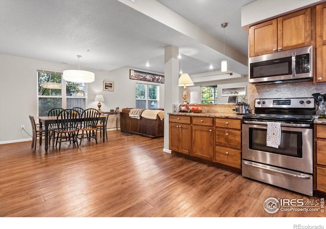 kitchen with decorative backsplash, pendant lighting, stainless steel appliances, and plenty of natural light