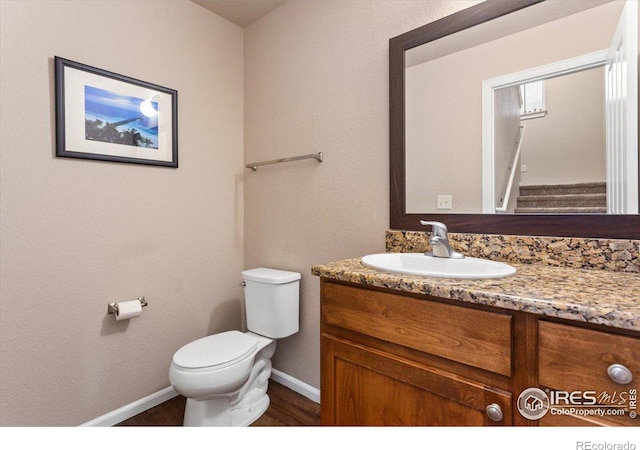 bathroom with hardwood / wood-style flooring, vanity, and toilet