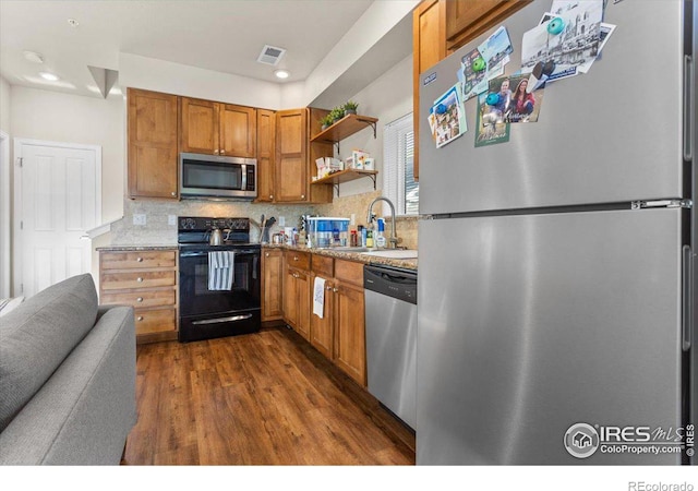 kitchen featuring backsplash, sink, dark hardwood / wood-style flooring, light stone counters, and stainless steel appliances