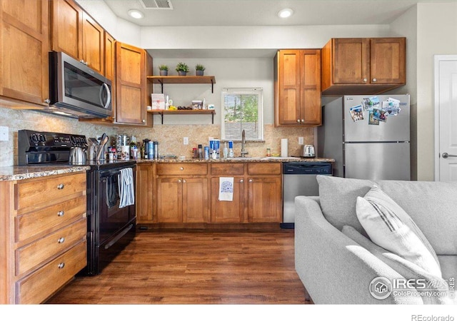 kitchen featuring sink, dark wood-type flooring, stainless steel appliances, tasteful backsplash, and light stone counters