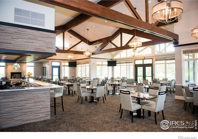 carpeted dining room with beamed ceiling, high vaulted ceiling, and a chandelier