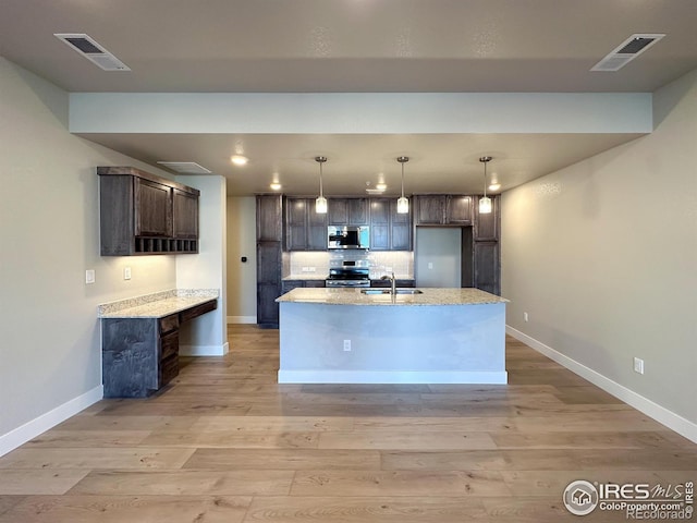 kitchen featuring dark brown cabinetry, sink, light stone counters, stainless steel appliances, and light hardwood / wood-style floors