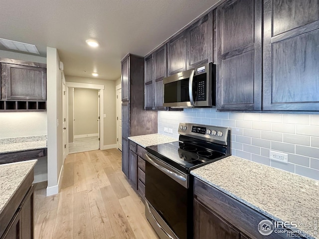 kitchen featuring stainless steel appliances, tasteful backsplash, light wood-type flooring, and light stone counters