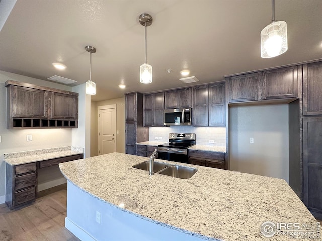 kitchen featuring pendant lighting, stainless steel appliances, light hardwood / wood-style floors, and decorative backsplash