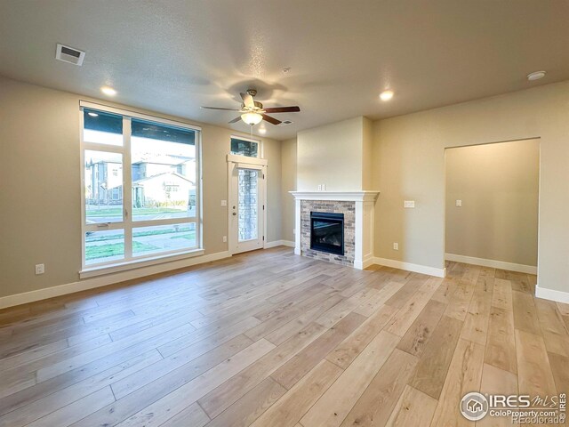 unfurnished living room with ceiling fan, light hardwood / wood-style flooring, and a textured ceiling