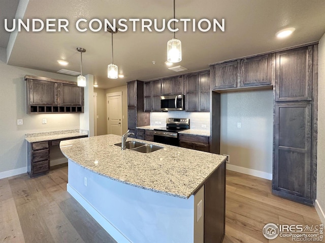 kitchen with hanging light fixtures, light stone counters, stainless steel appliances, dark brown cabinets, and a center island with sink