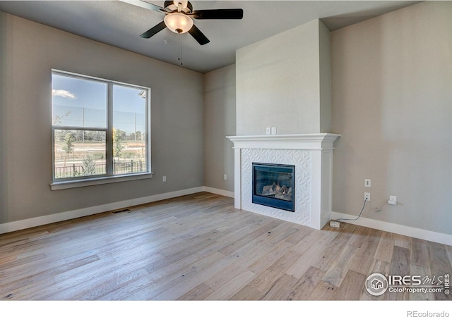 unfurnished living room featuring ceiling fan, light hardwood / wood-style floors, and a tile fireplace