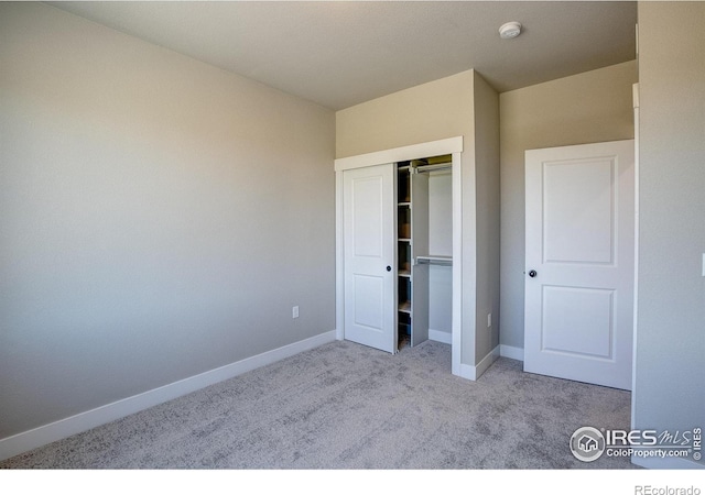 unfurnished bedroom with light carpet and a closet