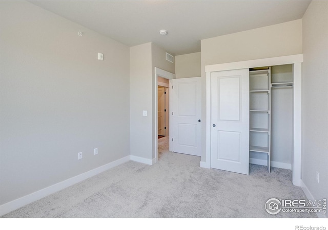 unfurnished bedroom featuring light carpet and a closet