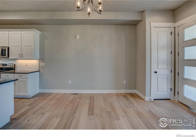 kitchen featuring white cabinetry, light hardwood / wood-style flooring, a notable chandelier, and appliances with stainless steel finishes