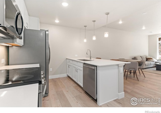 kitchen with pendant lighting, white cabinets, appliances with stainless steel finishes, light hardwood / wood-style floors, and sink