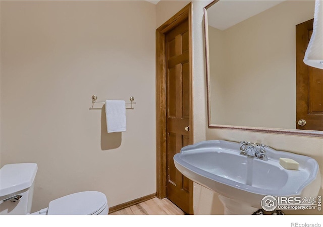 bathroom with hardwood / wood-style flooring, sink, and toilet