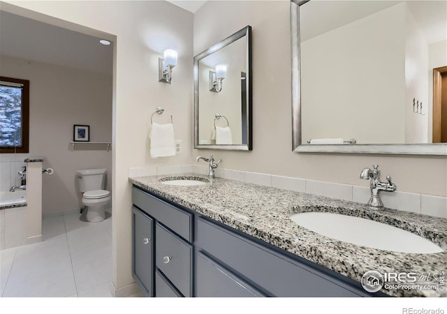 bathroom featuring tile patterned floors, vanity, a bathtub, and toilet