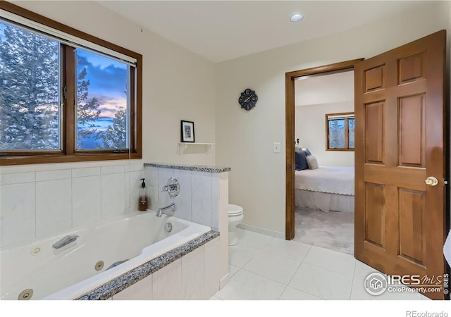 bathroom with tile patterned flooring, a relaxing tiled tub, toilet, and a healthy amount of sunlight