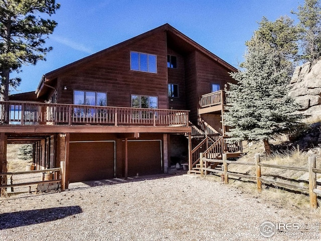 rear view of property featuring a garage and a wooden deck