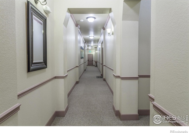 hall with crown molding and light carpet