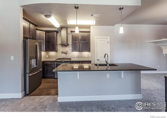 kitchen featuring sink, wall chimney range hood, dark colored carpet, a kitchen island with sink, and appliances with stainless steel finishes