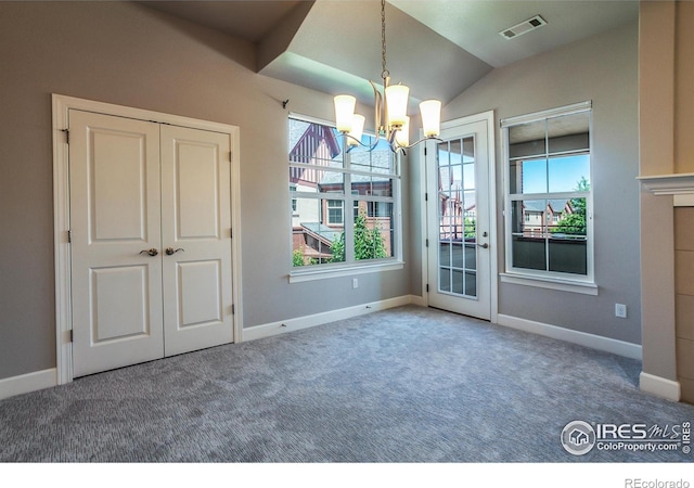 unfurnished dining area with carpet floors, an inviting chandelier, and vaulted ceiling