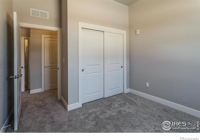 unfurnished bedroom with dark colored carpet and a closet