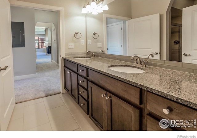 bathroom with tile patterned flooring, vanity, electric panel, and an inviting chandelier