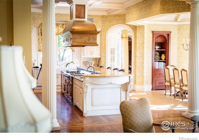 kitchen with beamed ceiling, ornate columns, premium range hood, coffered ceiling, and dark hardwood / wood-style flooring