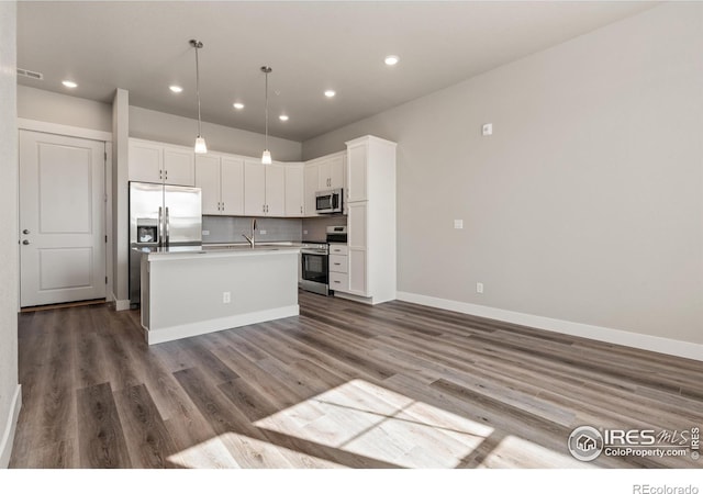 kitchen featuring white cabinets, pendant lighting, wood-type flooring, a kitchen island with sink, and stainless steel appliances