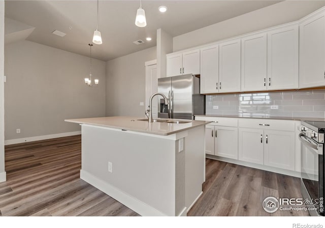 kitchen with stainless steel appliances, pendant lighting, an island with sink, and white cabinets