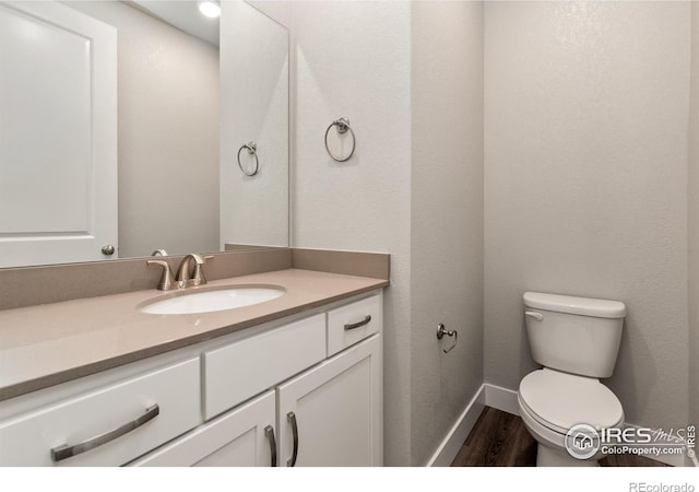 bathroom with wood-type flooring, vanity, and toilet