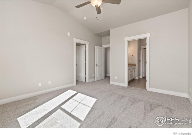 unfurnished bedroom featuring ensuite bath, ceiling fan, light colored carpet, and vaulted ceiling