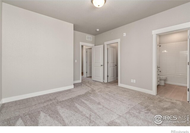 unfurnished bedroom with light colored carpet and ensuite bath