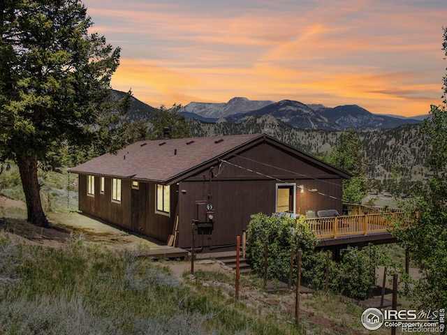 back house at dusk with a deck with mountain view