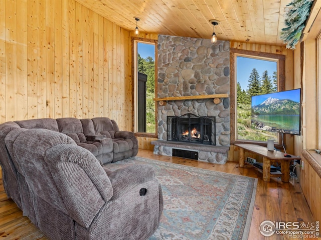 living room featuring wood ceiling, a stone fireplace, a wealth of natural light, and hardwood / wood-style flooring