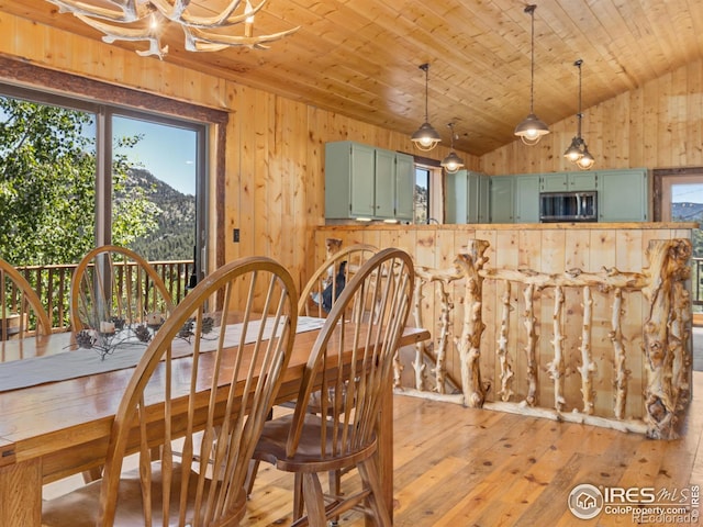 dining room featuring vaulted ceiling, light wood-type flooring, a mountain view, a chandelier, and wood ceiling