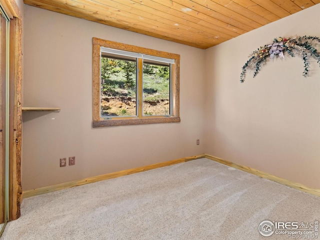 carpeted empty room featuring wood ceiling