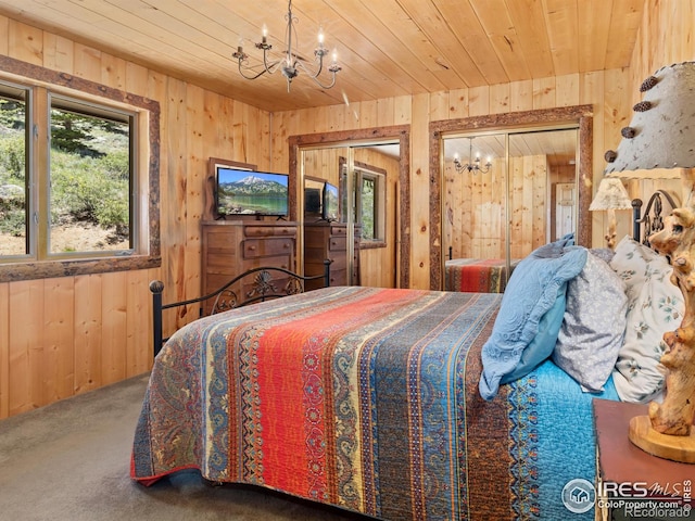 bedroom with a notable chandelier, wood ceiling, wood walls, and carpet floors