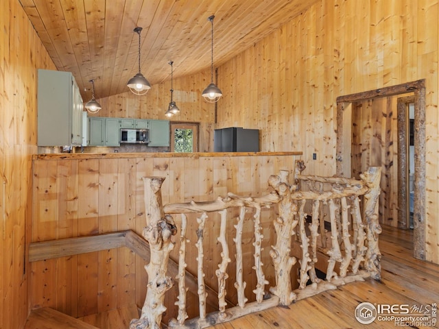 bar with wood ceiling, hardwood / wood-style floors, vaulted ceiling, wood walls, and decorative light fixtures