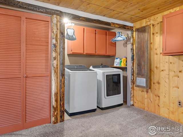 laundry area with washing machine and dryer, wooden walls, wooden ceiling, and cabinets