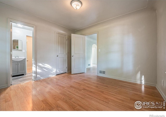 unfurnished bedroom featuring sink, connected bathroom, and light hardwood / wood-style flooring