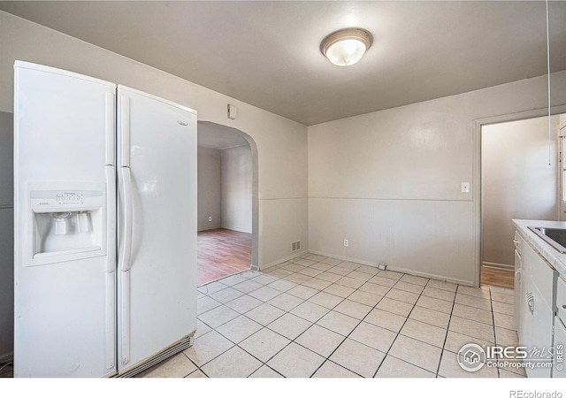 kitchen featuring light hardwood / wood-style flooring, white cabinets, and white refrigerator with ice dispenser