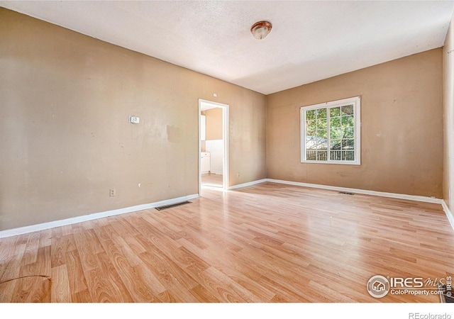 empty room featuring light wood-type flooring and a textured ceiling