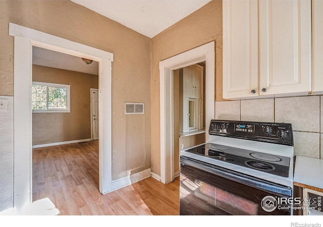 kitchen with white electric range oven, white cabinetry, and light hardwood / wood-style flooring