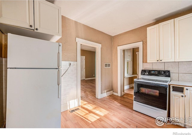 kitchen with white cabinets, white appliances, light hardwood / wood-style floors, and backsplash